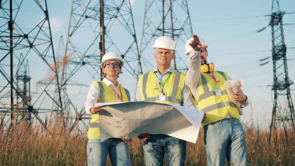 Engineers Check a Blueprint While Working with Power Lines.