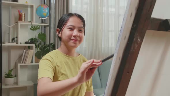 Asian Artist Girl Holding Paintbrush Mixed Colour And Painting On The Canvas