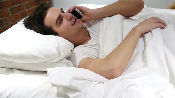 Man in Bed Answering call and Talking on Smartphone