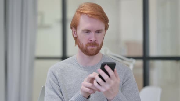 Young Beard Redhead Man Using Smartphone