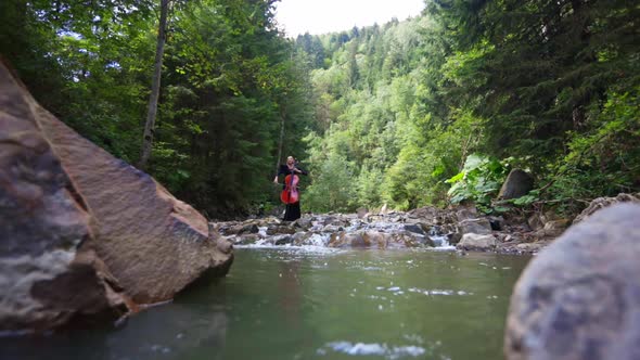 Female cellist among mountain river