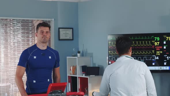 Handsome Athlete Being Tested and Monitored By Multiracial Doctor During Treadmill Test in Lab