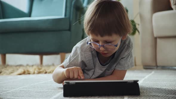 Child Using Tablet Lying on the Floor at Home Distance Learning Elearning Early Child Development