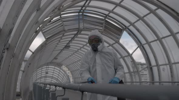 Worker Sprays a Disinfectant Solution on the Railing