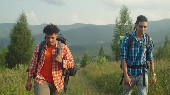 Positive Multiracial Male Travelers with Backpacks Using Compass for Navigation on Mountain Hiking