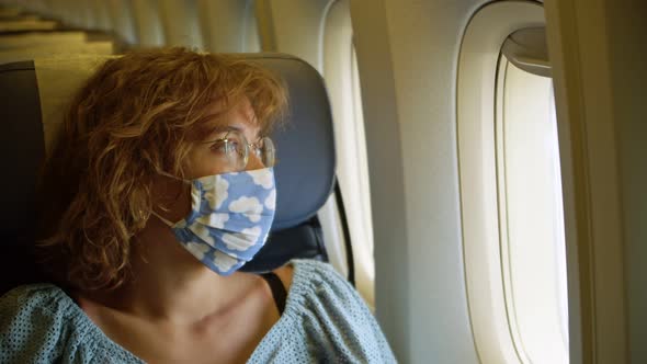 a Young Woman in a Protective Mask with the Image of Clouds Falls Asleep on the Plane