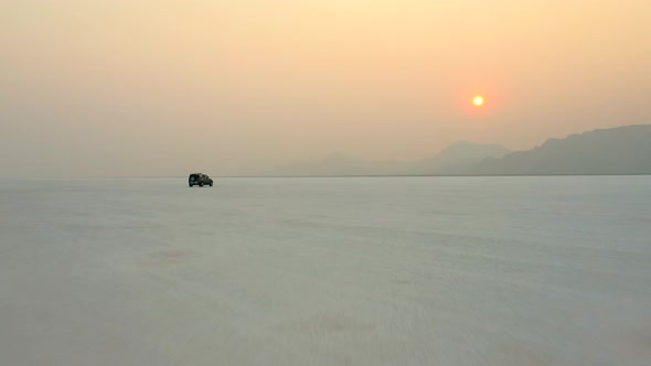 Traveling By 4x4 Car In Salt Flats With View Of Golden Sun In Sunset Sky. Bonneville, Utah, USA. - D