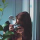 Woman photographer taking a picture of a plant, window reflection - VideoHive Item for Sale