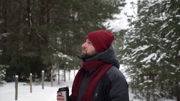 Young Man in Winter Forest Walking Drinking Hot Coffee