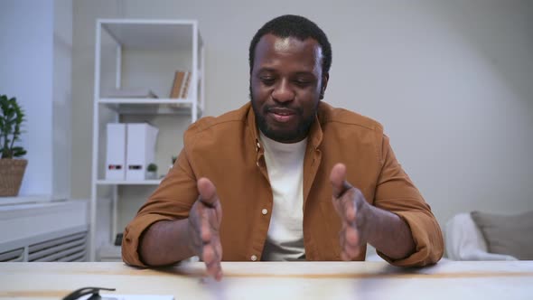 African Man Gestures with Hand at White Table in Room Spbas