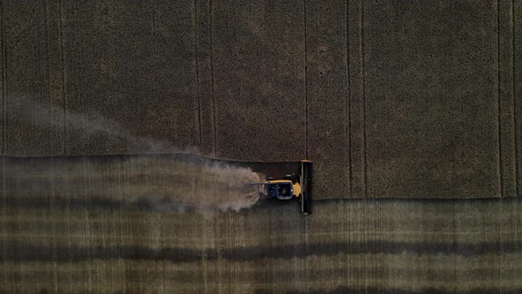 Aerial drone view from above of a modern combine harvester reaping cereals at sunset in Alberta, Can