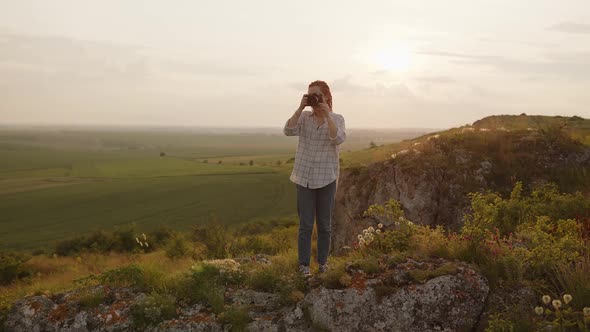 Girl Stands on a High Mountain and Takes Photos