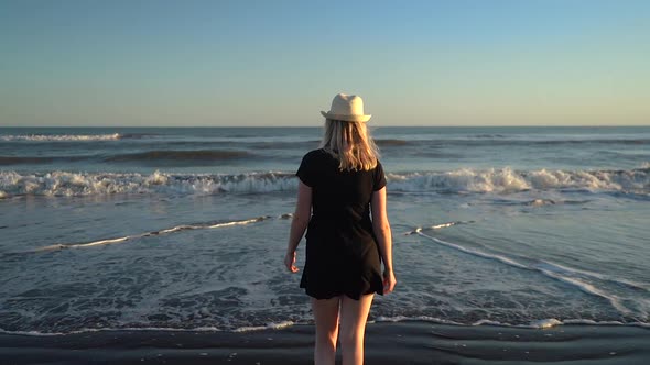 Attractive Woman In Summer Dress Walking Towards Sandy Beach With Rolling Waves At Monte Hermoso, Bu