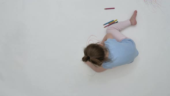 Girl Draws on the Floor with Pencils with Two Hands