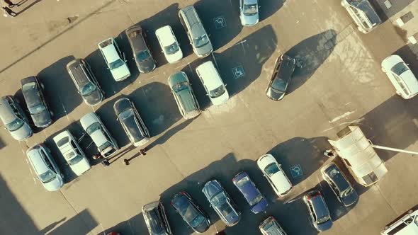 Top aerial view of many cars on a parking lot of supermarket or on sale car dealer market.