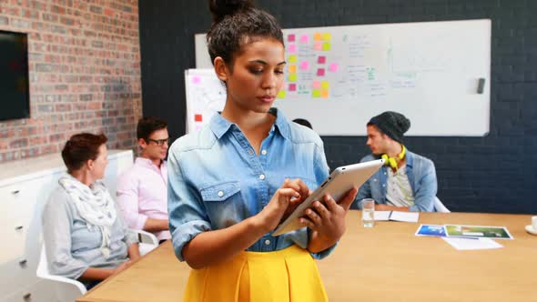 Businesswoman using digital tablet while coworkers interacting with each other