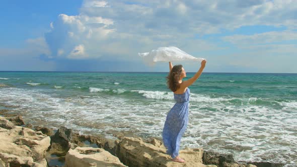 Slow Motion of Beautiful Lady in Long Dress Waving White Scarf on Rocky Beach