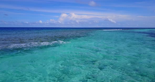 Daytime aerial island view of a sandy white paradise beach and blue sea background in vibrant 4K