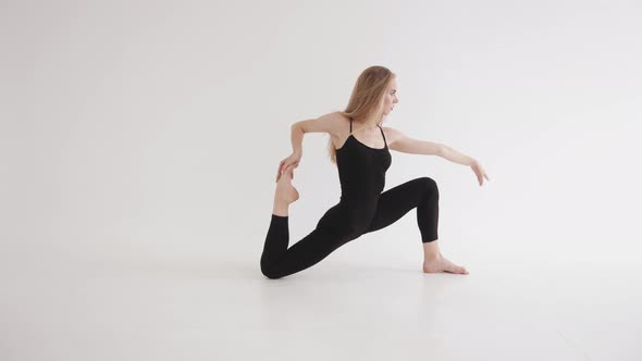 Adorable Young Girl in Tight Black Clothes Doing Stretching in a White Studio and Lunge Hand Grip