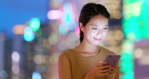 Woman use of mobile phone in city of Hong Kong at night