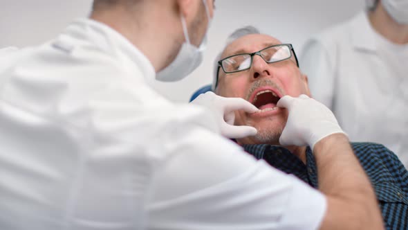 Close Up Male Dentist Trying False Jaw Sample to Senior Man at Dentistry
