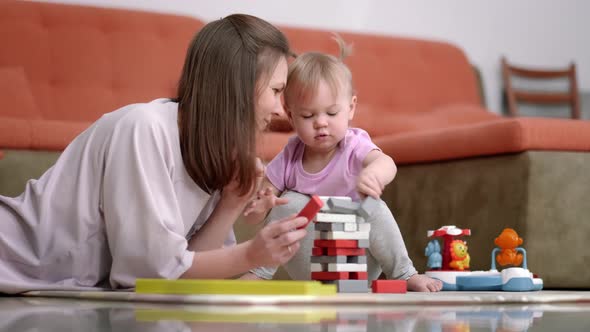 Little Baby Girl and Mommy Playing Color Wooden Toys at Home Sitting on Floor Mother and Daughter