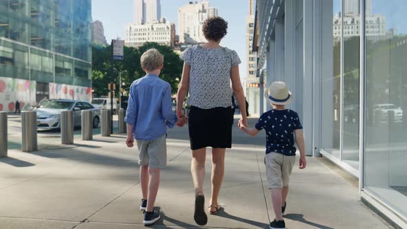 Mother Walking Hand In Hand With Her Two Sons Through New York City Streets