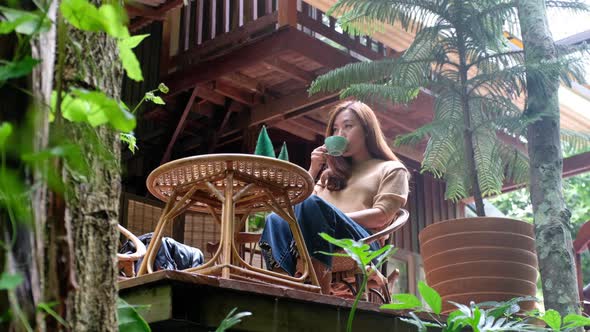 A beautiful young asian woman sitting and hanging legs in the forest