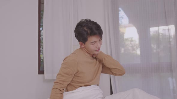 Asian Man Waking Up in Bed Smilling in Morning. Man at Home in Bed Stretching. Lifestyle Concept