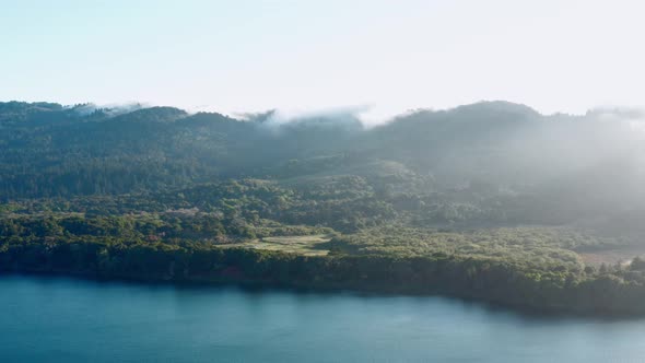 Aerial: Half Moon Bay Lake, Mountains and Fog. Panning Right