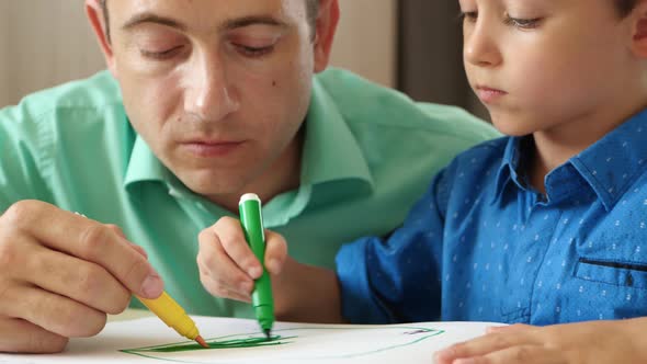 A Father Spends Time Drawing with Colored Pencils with His Son, Passionate About the Game Dad and Son