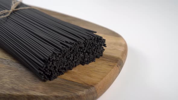 Black dry organic spaghetti with cuttlefish ink on a wooden surface