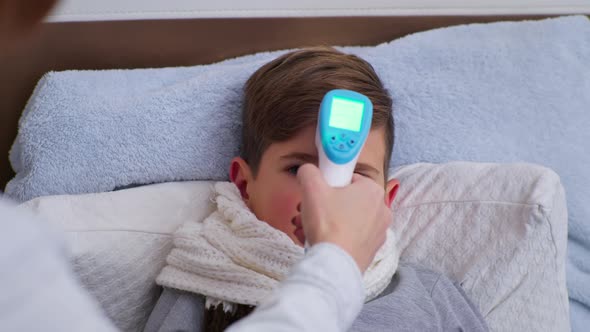 Unhealthy Male Child Has High Temperature Measured with Noncontact Thermometer in Fahrenheit Degrees