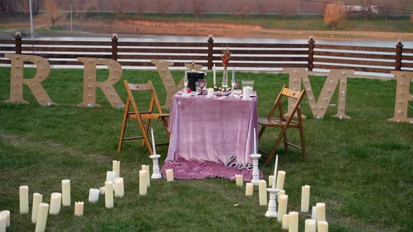 Beautifully Arranged Table on the Edge of the Fenced Lake on the Green Meadow