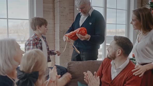 Grandad Opens His Gift on Christmas Morning and Hugging His Grandson