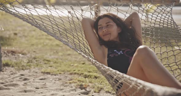 Pretty Amazing Cheerful Young Girl on the Beach, Lying in a Hammock and Smiling in a Black Sexy