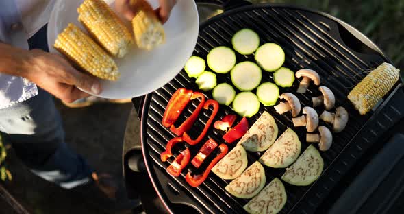 Close up on man's hand roasting vegetables on the barbecue gas grill