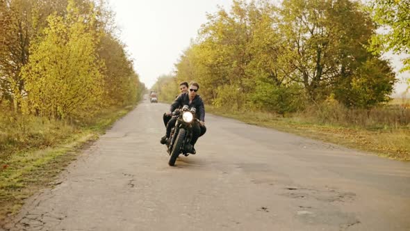 Tracking Shot of Couple Riding Motorcycle on Forest Road in Autumn