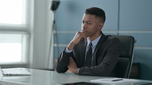 Pensive African Businessman Thinking While Sitting in Office