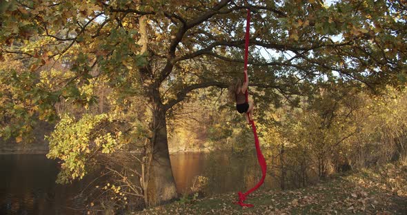 Flexible Brunette With Bare Feet Hanging On A Canvas For Aerial Acrobatics Outdoors.