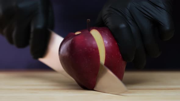 Cuts an apple in half with a knife