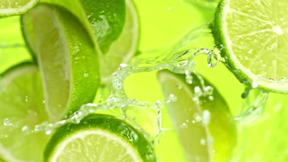 Super Slow Motion Shot of Lime Slices Falling Into Water on Green Background at 1000Fps.