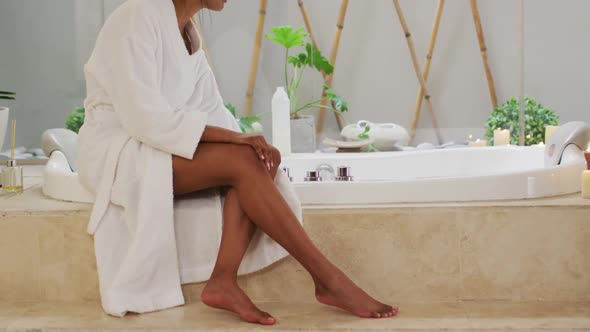 Mixed race woman sitting by a bathtub at home