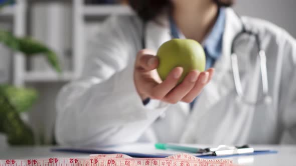 The Hand Of A Nutritionist Doctor Holds Out An Apple. The Hand Gives An Apple. A Nutritionist Give