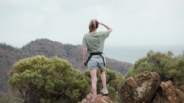 Woman Stands Alone on the Mountain High Looking Into the Distance