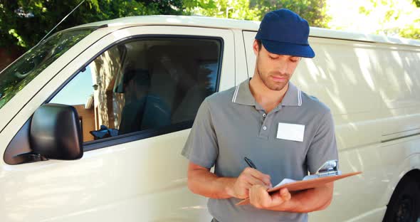 Delivery man writing on clipboard