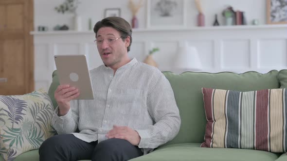 Man Talking on Video Call on Tablet on Sofa