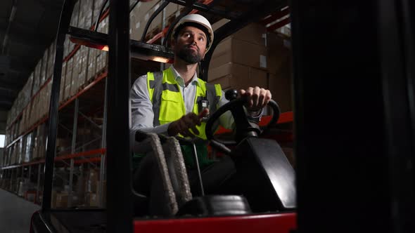 Male Warehouse Worker Driving Forklift in Reverse