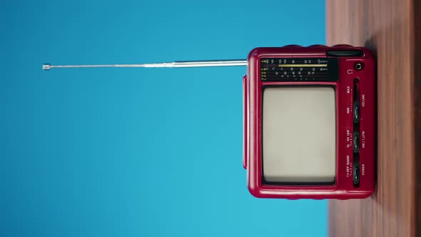 Vertical Video of Turning on Small Old Television with Grey Interference Screen on Blue Background