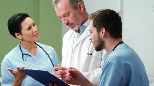 Three doctors discussing over digital tablet